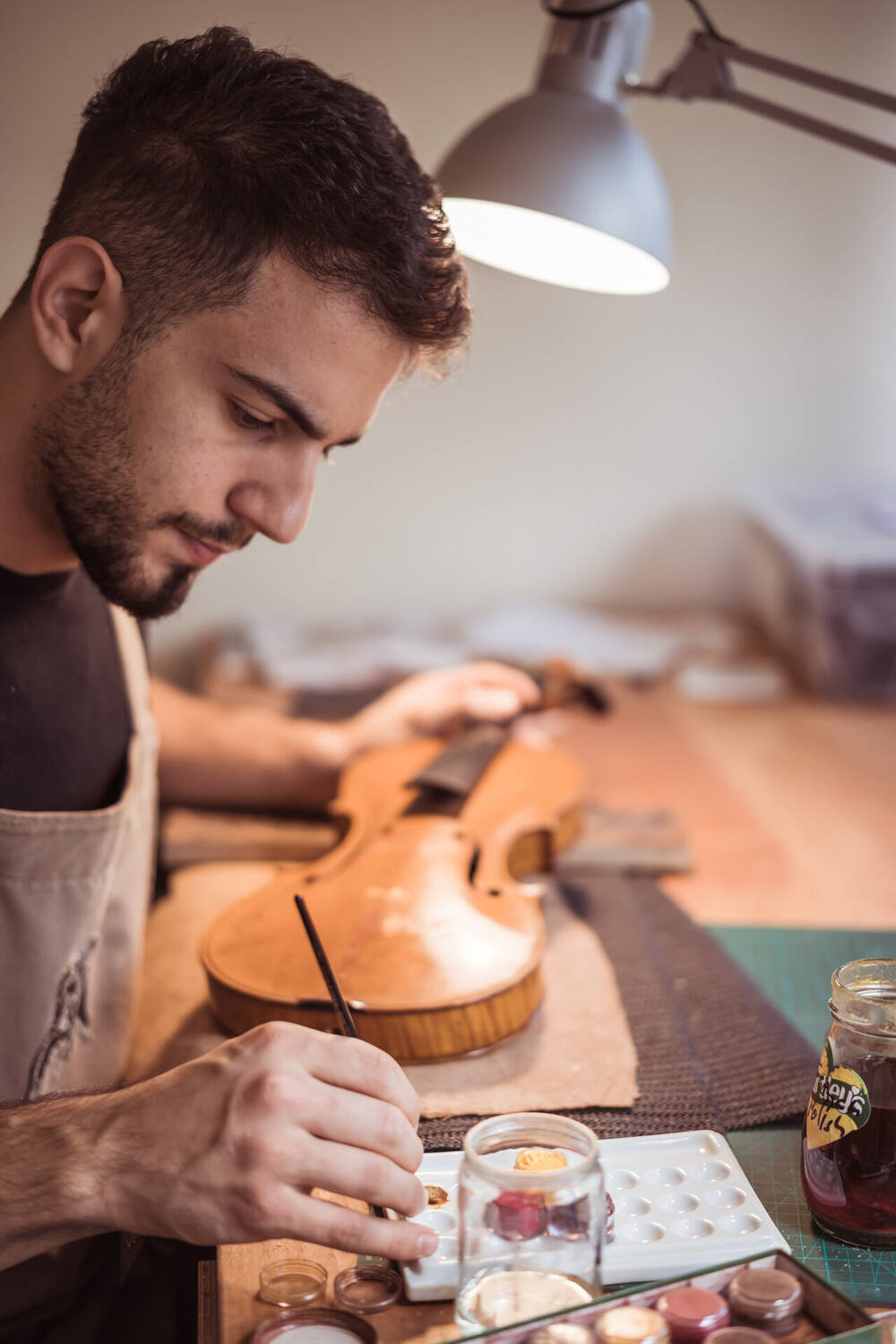 Marios retouching varnish on an instrument in the workshop