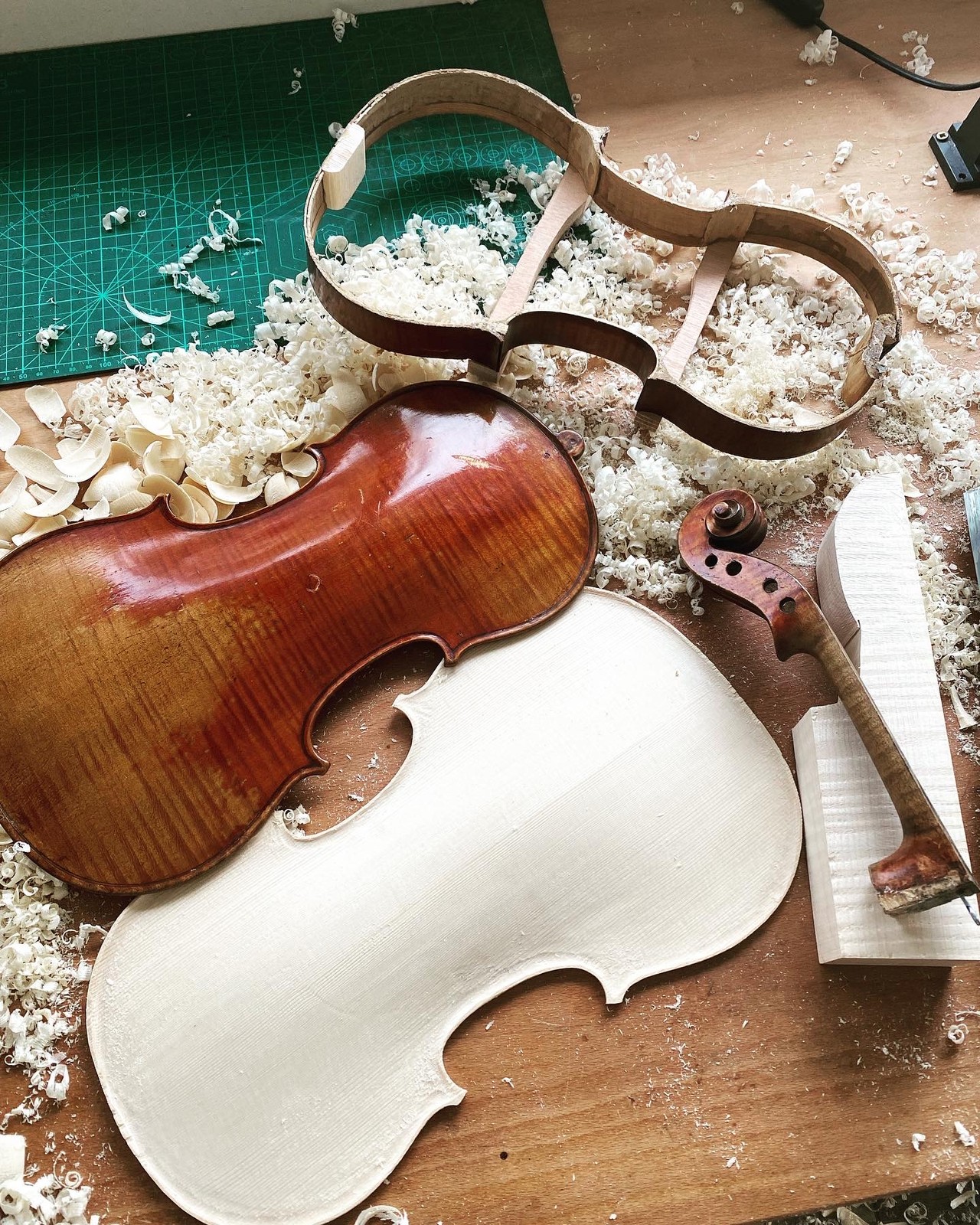 A retouched violin back beside plates in progress